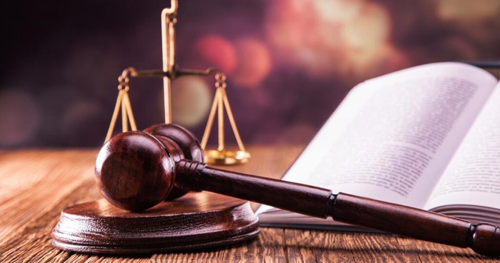 ميزان العدل والمطرقة مع القانون الذي يوضح أركان جريمة الابتزاز العاطفي في السعودية