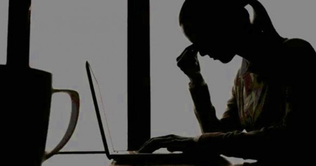 فتاة تبكي وأمامها لا بتوب بعد تعرضها لجريمة ابتزاز عاطفي وتهديد لها